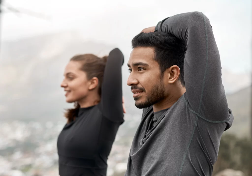 man and woman stretching during outdoor workout ov utc